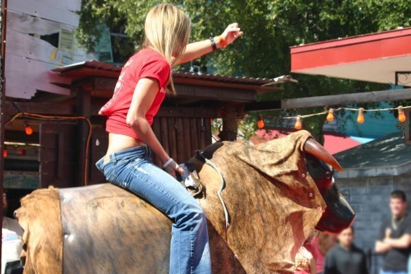 Blonde girl riding a mechanical bull outside for the Professional Bull Riding event in Ocean City, Maryland